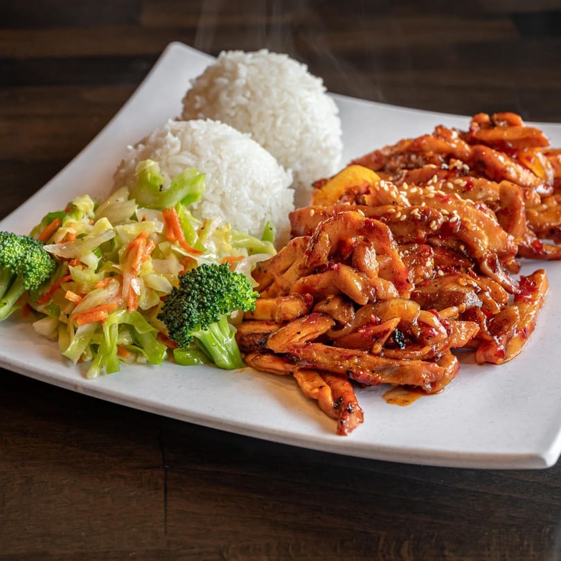 Nara Teriyaki and Pho's spicy teriyaki chicken with rice, broccoli, and cabbage on a white plate.